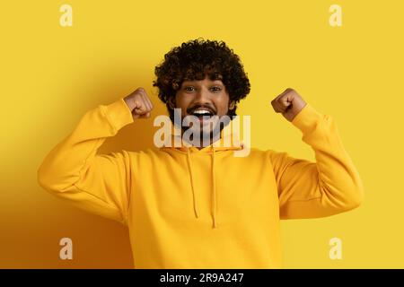 Un giovane indiano millenario che alza le mani e stringe i pugni Foto Stock