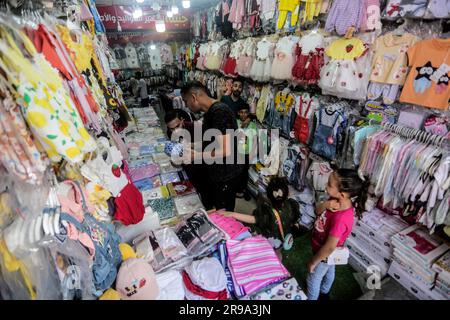 25 giugno 2023, Gaza City, Striscia di Gaza, Palestina: I palestinesi fanno shopping in un mercato davanti a Eid al-Adha nella città di Gaza. I gazani comprano più vestiti in preparazione per l'imminente Festa del sacrificio. EID al-Adha è la festa più sacra dei musulmani celebrata ogni anno e segna il pellegrinaggio annuale per visitare la Mecca, il luogo più sacro dell'Islam. I musulmani massacrano il sacrificio e dividono la carne in tre parti, una per la famiglia, un'altra per amici e parenti, e un'altra per i poveri e i bisognosi. (Immagine di credito: © Mahmoud Issa/Quds Net News via ZUMA Press Wire) SOLO USO EDITORIALE! No Foto Stock