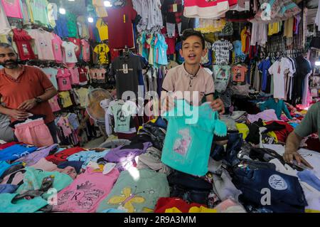 25 giugno 2023, Gaza City, Striscia di Gaza, Palestina: I palestinesi fanno shopping in un mercato davanti a Eid al-Adha nella città di Gaza. I gazani comprano più vestiti in preparazione per l'imminente Festa del sacrificio. EID al-Adha è la festa più sacra dei musulmani celebrata ogni anno e segna il pellegrinaggio annuale per visitare la Mecca, il luogo più sacro dell'Islam. I musulmani massacrano il sacrificio e dividono la carne in tre parti, una per la famiglia, un'altra per amici e parenti, e un'altra per i poveri e i bisognosi. (Immagine di credito: © Mahmoud Issa/Quds Net News via ZUMA Press Wire) SOLO USO EDITORIALE! No Foto Stock