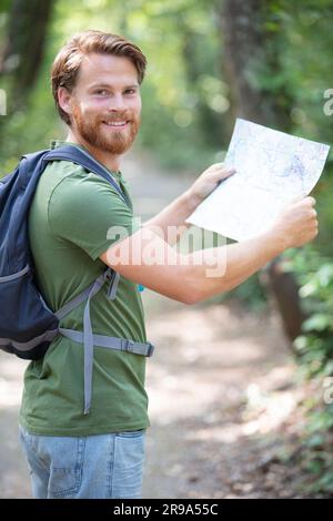 uomo con zaino e mappa alla ricerca di indicazioni nella zona selvaggia Foto Stock