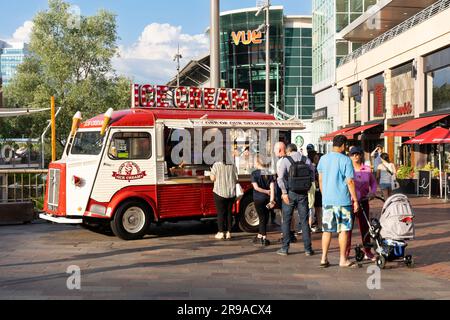 Durante una calda giornata estiva sull'Oracle Riverside, vicino al fiume Kennet, gli ospiti fanno la fila per un gelato pluripremiato da un furgone del gelato. Reading, Regno Unito Foto Stock