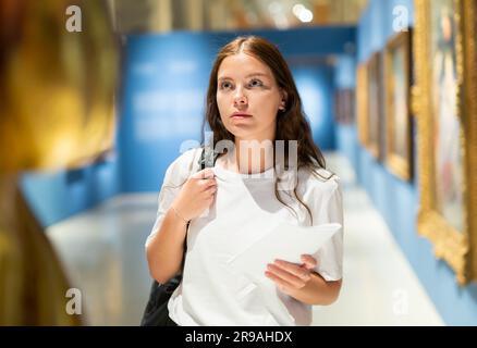 Una ragazza focalizzata visita una mostra in una galleria d'arte Foto Stock