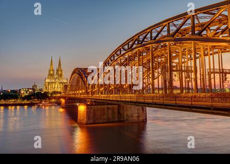 Il ponte illuminato Hohenzollern presso la cattedrale di Colonia dopo il tramonto Foto Stock