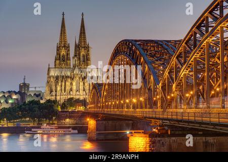 L'imponente cattedrale di Colonia e il ponte Hohenzollern sul Reno dopo il tramonto Foto Stock
