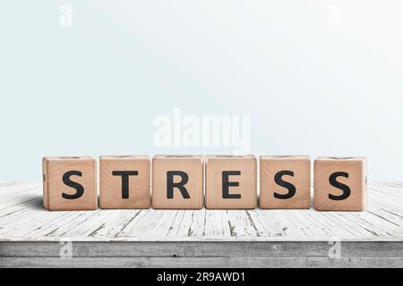 La parola stress su un segno fatto di blocchi di legno in una stanza luminosa su un tavolo Foto Stock