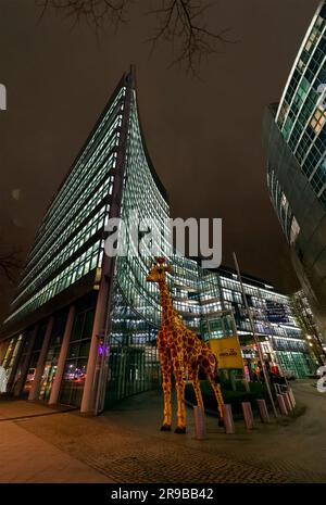 Berlino, Germania - 17 dicembre 2021: Gigantesca statua di giraffa di plastica davanti al Legoland Discovery Center, ripresa notturna a Berlino, Germania. Foto Stock