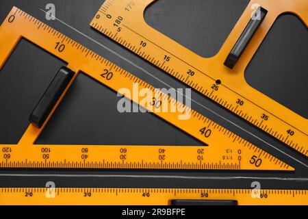 Triangolo, goniometro, righello e angolo acuto disegnato su tavolo nero, piatto Foto Stock