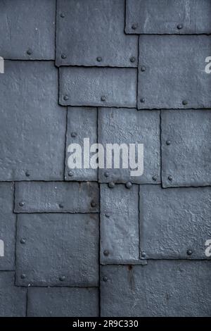 Sfondo con trama di superficie metallica grunge, frammento in rilievo da vicino con chiodi e patch saldati Foto Stock