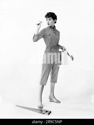 Stati Uniti: c. 1957 Una giovane donna in eleganti tute di cotone si prepara per alcune riparazioni domestiche. Foto Stock