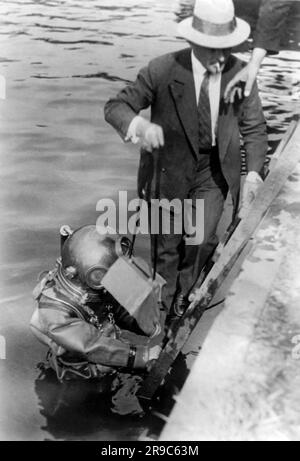 Berlino, Germania: c. 1932 il fotografo e fotoreporter Willie Ruge si prepara a salire a bordo del tender dei subacquei dopo il loro tentativo di scattare le prime fotografie subacquee fuori da una campana. La borsa del caricatore della fotocamera non funzionava, quindi questo viaggio è stato vano. Ci proveranno di nuovo. Foto Stock