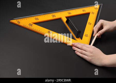 Donna che disegna con gesso e righello triangolare su lavagna, primo piano. Spazio per il testo Foto Stock