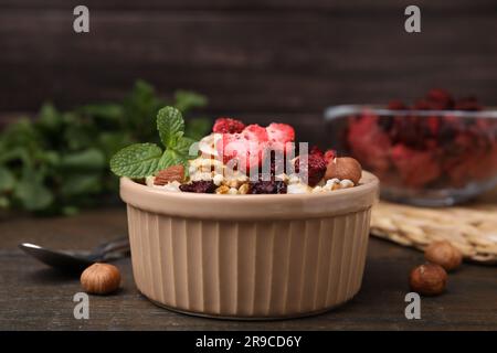 Farina d'avena con frutta secca liofilizzata, noci e menta su tavolo di legno, primo piano Foto Stock