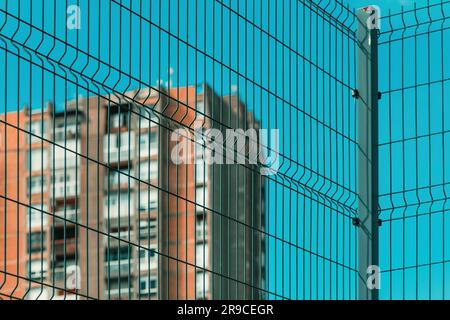 Alto edificio di appartamenti in stile brutalismo architettonico dietro una recinzione metallica, a fuoco selettivo Foto Stock