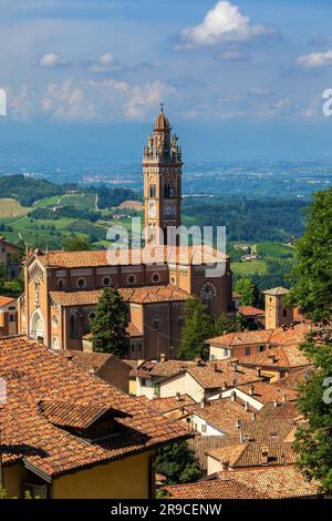 Veduta della chiesa con l'alta torre delle campane tra vecchie case con tetti rossi nella cittadina di Monforte d'Alba in Piemonte, Italia. Foto Stock