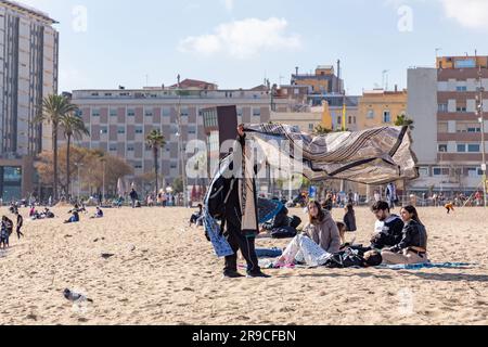 Barcellona, Spagna - FEB 10, 2022: Venditori illegali di stoffa da spiaggia sulla spiaggia di Barceloneta. Foto Stock