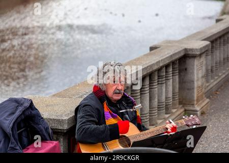 Girona, Catalogna, Spagna - FEB 12, 2022: Chitarrista solista esibendosi all'esterno, presso il fiume Onyar a Girona, Spagna. Foto Stock
