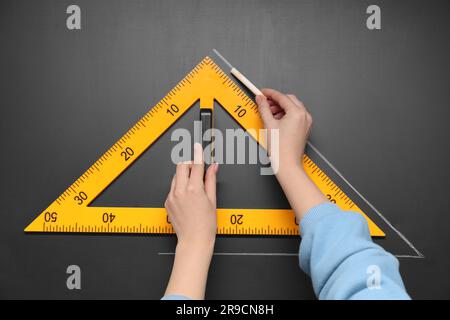 Donna che disegna con gesso e righello triangolare su lavagna, primo piano Foto Stock