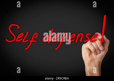 Uomo che scrive parole autodifesa con un pennarello su lastra di vetro su sfondo nero, primo piano Foto Stock