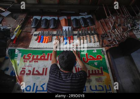 Gaza City, Palestina. 25 giugno 2023. Un impegnato laboratorio di affilatura dei coltelli nella città di Gaza, in vista delle prossime celebrazioni di Eid al-Adha il 25 giugno 2023. EID al-Adha o ''Festa del sacrificio'' è una grande festa nell'Islam che viene celebrata l'ultimo giorno del pellegrinaggio Hajj. È tradizione sacrificare un animale come una pecora o una capra durante Eid al-Adha, per ricordare l'obbedienza del Profeta Ibrahim a Dio. Foto di Habboub Ramez/ABACAPRESS.COM credito: Abaca Press/Alamy Live News Foto Stock