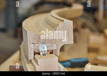 Curvatura del corrimano della scala in legno realizzato con tavole di rovere e compensato in primo piano. Dettaglio della recinzione delle scale in officina di falegnameria Foto Stock