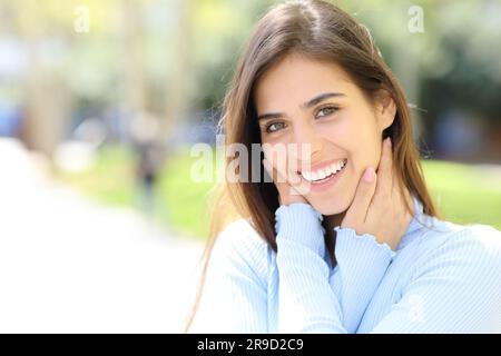 Bella donna dai denti bianchi che sorride guardando la macchina fotografica in strada Foto Stock