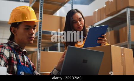 Giovane che pianifica la distribuzione degli ordini in deposito, lavora con donna per inviare pacchi di vendita al dettaglio per la catena di approvvigionamento. Team di dipendenti che controllano merci e prodotti, sviluppo aziendale. Foto Stock