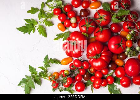 Vari pomodori freschi con foglie verdi. Vista dall'alto Foto Stock
