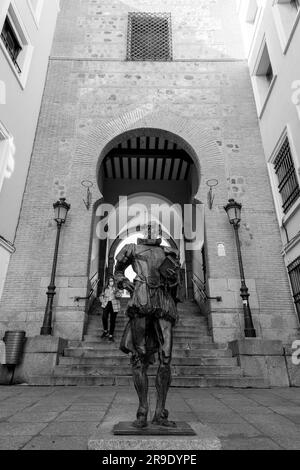 Toledo, Spagna-FEB 17, 2022: Statua di Cervantes presso l'Arco de la Sangre, storica porta araba della città, ex Bab-al-Yayl nella vecchia città imperiale di Foto Stock