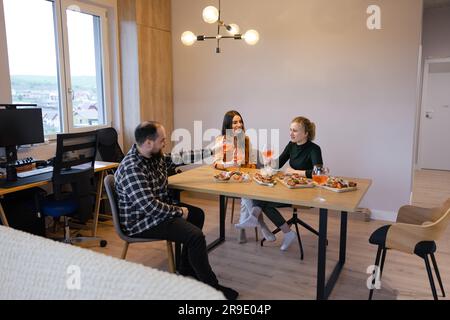 Amici di Thrre che si godono cibo e bevande a casa Foto Stock