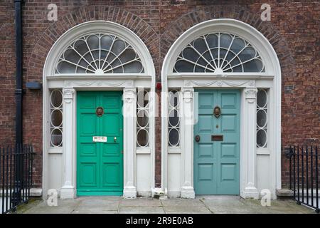Un paio di porte anteriori vicine in stile georgiano con finestra a specchio di poppa decorata Foto Stock