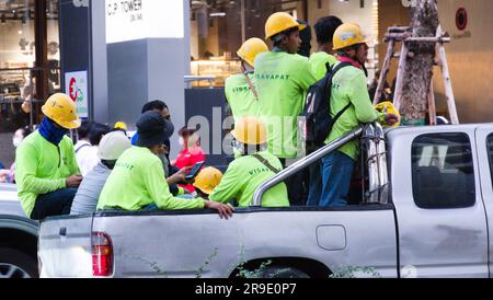 Gli operai edili che indossano cappelli duri tornano a casa in piedi o si siedono sul retro di un camion nell'ora di punta dopo il lavoro su Silom Road, Bangkok, Thailandia. Anche se questo è stato reso illegale nel 2017 per motivi di sicurezza questo è ancora un modo comune ed economico per viaggiare in Thailandia. Foto Stock