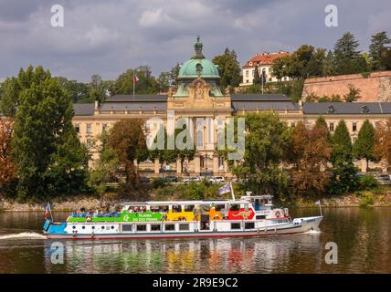 PRAGA, REPUBBLICA CECA, EUROPA - crociera in barca con turisti sul fiume Moldava, passa davanti all'edificio dell'Accademia Straka, l'ufficio del governo della Repubblica Ceca Foto Stock