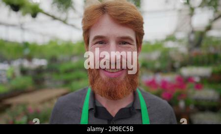 Ritratto di un lavoratore felice di testa rossa che indossa grembiule verde all'interno del fioraio. Concetto aziendale locale di dipendente MAN Foto Stock