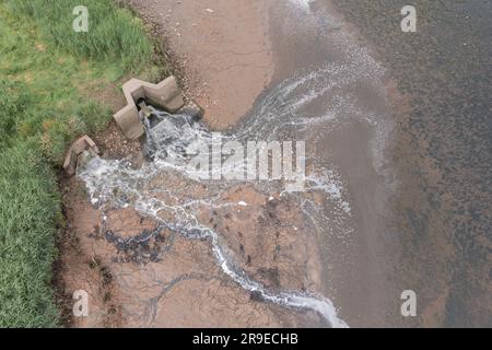 Vista aerea del primo latte (a sinistra) e dello scarico del tubo dell'acqua gallese nell'estuario di Cleddau. La superficie fangosa intertidale è scolorita in rosso a causa del deposito Foto Stock