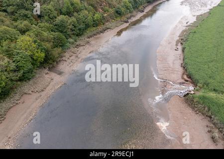 Vista aerea del primo scarico del latte (far) e del tubo dell'acqua gallese nell'estuario di Cleddau. La superficie fangosa intertidale è scolorita in rosso a causa del deposito Foto Stock