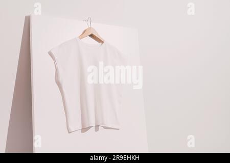 Mockup bianco bianco bianco t-shirt, modello su appendiabiti in legno Foto Stock