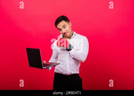 Un tizio con guanti da boxe e formalwear un computer da pugno isolato con il cyber bullismo rosso. Foto Stock