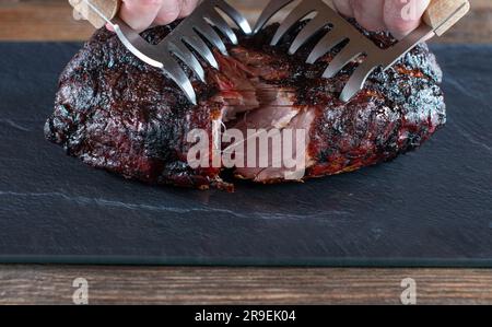 La carne di maiale fresca intera viene fatta a pezzi con le forchette Foto Stock