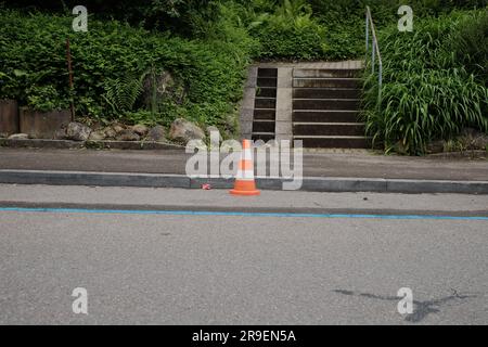 La sicurezza prima di tutto nelle zone di costruzione. I lavoratori che lavorano con elmetti arancioni riparano le strade, garantendo la protezione del traffico e dei lavoratori. Foto Stock