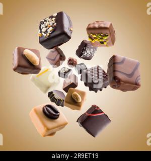 Praline di cioccolato assortite che cadono su sfondo colorato Foto Stock