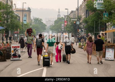 Montreal, CA - 24 giugno 2023: Gente che cammina su Mont-Royal avenue mentre la città è nel fumo degli incendi boschivi canadesi Foto Stock