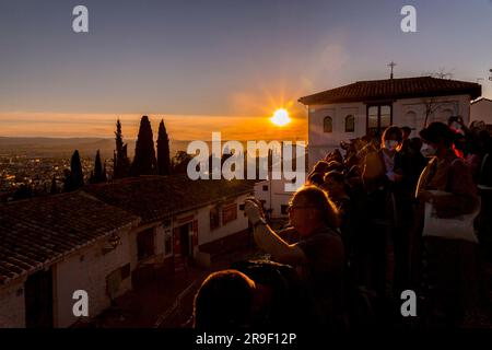 Granada, Spagna - 22 febbraio 2022: Folla di visitatori che guarda il tramonto e osserva il Palazzo dell'Alhambra dal Mirador de San Nicolas, Granada, Spai Foto Stock