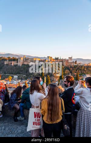 Granada, Spagna - 22 febbraio 2022: Folla di visitatori che guarda il tramonto e osserva il Palazzo dell'Alhambra dal Mirador de San Nicolas, Granada, Spai Foto Stock