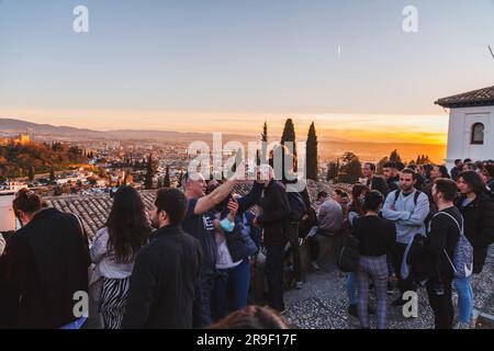 Granada, Spagna - 22 febbraio 2022: Folla di visitatori che guarda il tramonto e osserva il Palazzo dell'Alhambra dal Mirador de San Nicolas, Granada, Spai Foto Stock