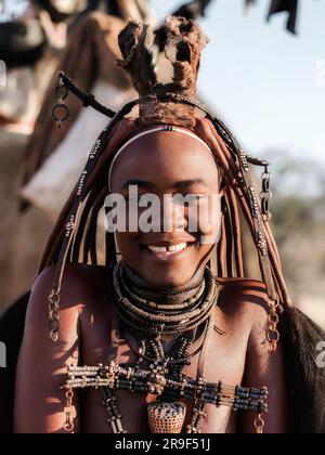 Giovane donna Himba sorridente, vestita in stile tradizionale nel suo villaggio in Namibia, in Africa. Foto Stock