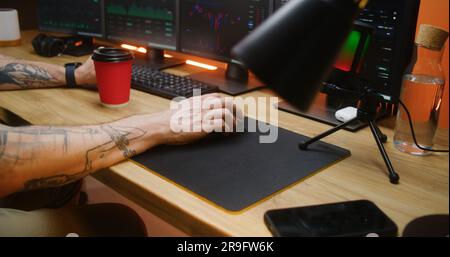 Il trader maschile utilizza mouse per computer, tipi su tastiera, analizza azioni in tempo reale, grafici di mercato di borsa su PC multi-monitor. Man lavora in remoto in investimenti o criptovalute in ufficio. Primo piano. Foto Stock