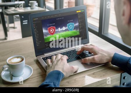 L'uomo segue il risultato della partita di calcio su un notebook. Concetto di scommesse online e punteggio live Foto Stock