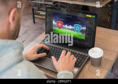 Concetto di scommesse online dal vivo. Man guarda il punteggio dal vivo della partita e le quote per le scommesse dal vivo Foto Stock