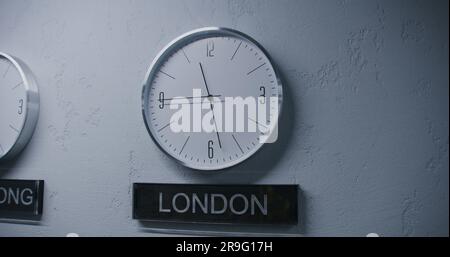 Gli orologi bianchi con indicatori del tempo di esecuzione mostrano i fusi orari di diverse città. Orologi da parete da passeggio in ufficio dal design moderno. Nomi di grandi città scritte sotto orologi. Interni rigidi. Dolly shot. Foto Stock