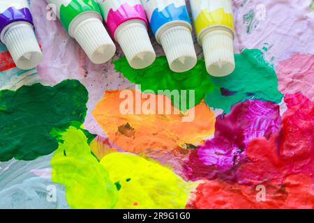 Tubi di vernice colorata sullo sfondo di una tavolozza luminosa e multicolore dell'artista in primo piano. Foto Stock